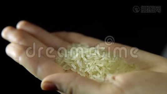 女性手指的特写在黑色背景上用手搅拌米饭。视频