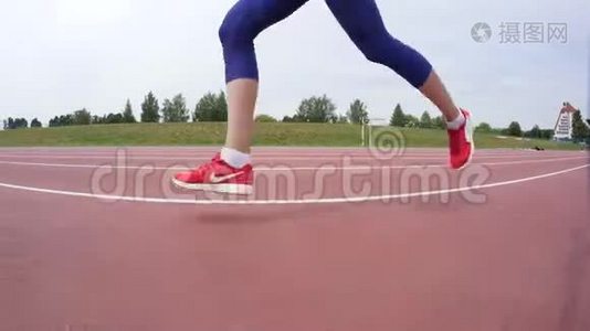 一名穿红色短裙的年轻女子在城市体育场馆的一天跑步训练中跑过镜头视频