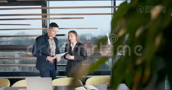 男人和女人在灯火通明的现代办公室里讨论工作。 从事图表文件工作的有关男女视频