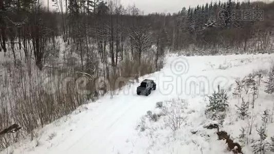 一辆6x6越野车的鸟瞰图，它在冬天森林里的雪覆盖的道路上行驶视频