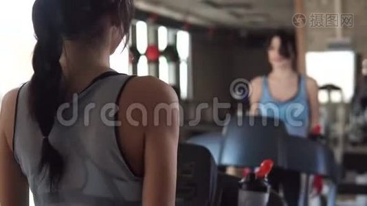 年轻女子在健身房里喝干净的水锻炼。 一个女孩在跑步机上行走视频