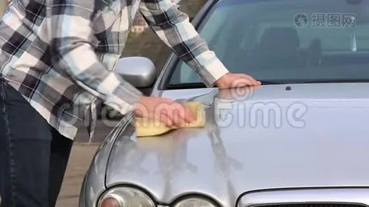 这个人用海绵仔细地清洗他最喜欢的汽车。洗车自助服务视频