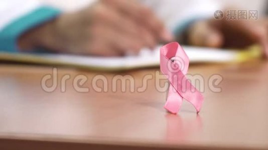 一位医生桌子上的粉红色丝带乳腺癌意识符号视频