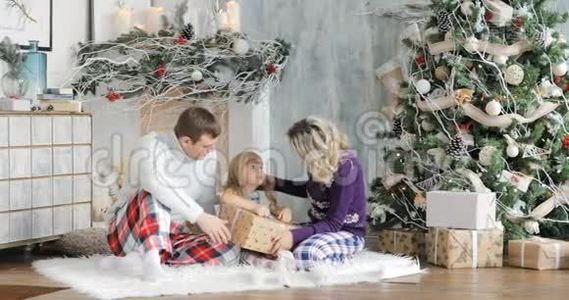 父母和女儿在客厅里玩圣诞礼物。 盒子里有圣诞礼物给孩子。 A.视频