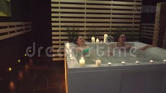 两个快乐的朋友在按摩浴缸里休息，在水疗中心饱含海盐视频