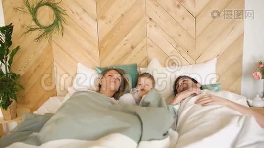 年轻有趣的男孩醒来时，他的父母早上睡在他们家的床上视频