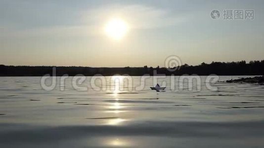 夕阳西下，一只稚气的纸船在林湖中漂浮视频