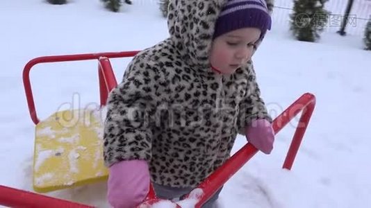 冬天下雪的时候，小女孩在操场上摇摆。 4K视频