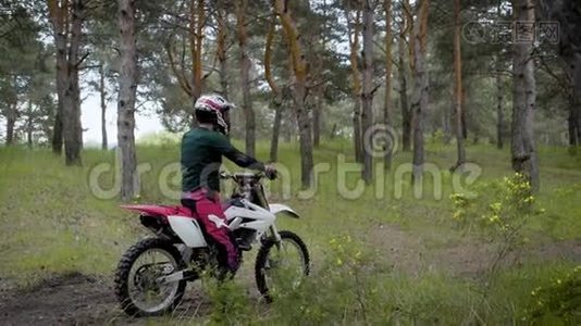 一个骑着制服戴着防护头盔的摩托车手正骑着一辆车沿着乡村公路穿过森林视频