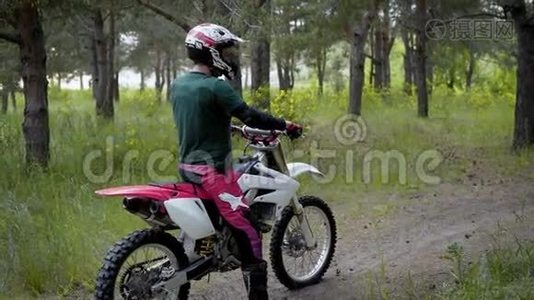 一个戴着防护头盔和特殊制服的运动员骑着越野摩托车在大自然中的森林中视频