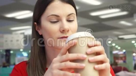 在食品场的快餐店里，一个口渴的女孩从纸杯里喝咖啡。视频