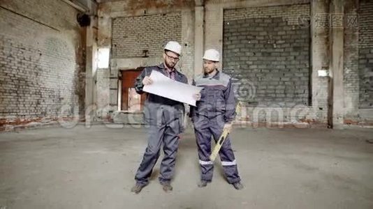 有计划的人在施工。 两名穿制服的建筑工人站在现场背景上探索视频