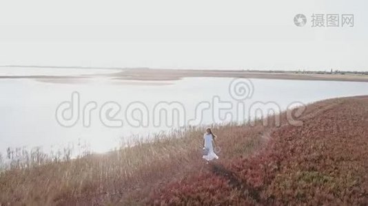 穿着白色裙子的女孩沿着海滨散步视频