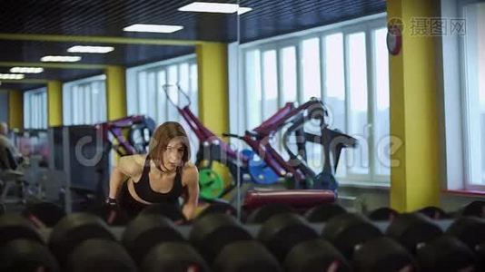 一个运动的女人看着镜子，泵着前臂的肌肉。视频
