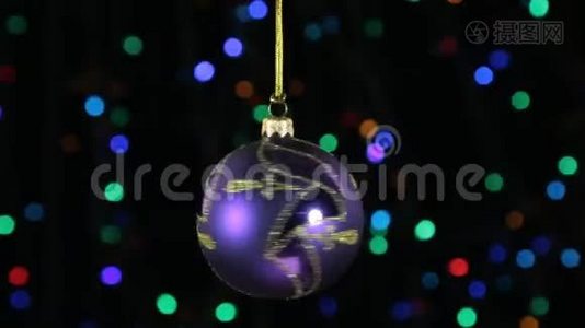 特写，旋转的紫丁香圣诞球挂在一根金色的绳子上.. 圣诞节和新年装饰。视频