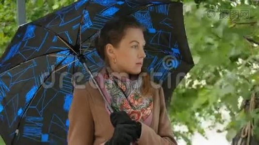 美丽的女孩躲在雨下的伞下视频