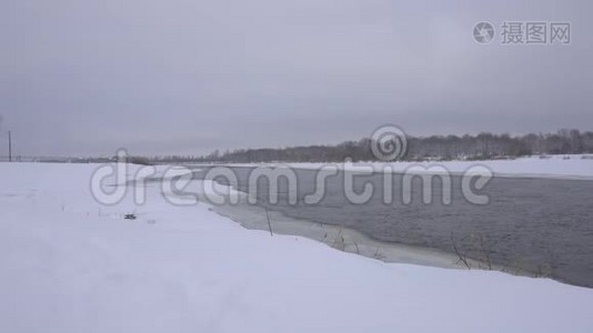 雪中一条冬季河流的景观，背景是一片雪林，4K，天然视频