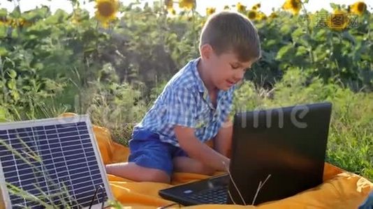 现代童年，快乐的孩子使用太阳能电池充电笔记本电脑背景领域向日葵，孩子看着视频