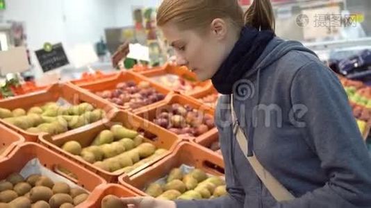 美丽迷人的年轻女人在超市挑选猕猴桃水果。 健康的饮食观念。视频