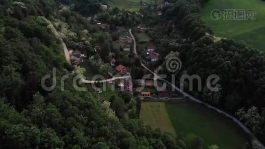 空中无人驾驶飞机在日落时分飞过被森林包围的东欧山村。 夏天绿树成荫.视频