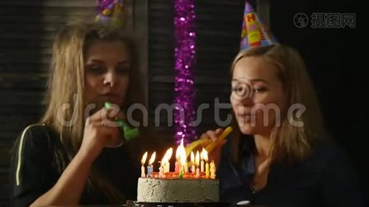 两个喜怒无常的女人吹灭了生日蛋糕上的蜡烛，蜡烛熄灭了。慢动作视频