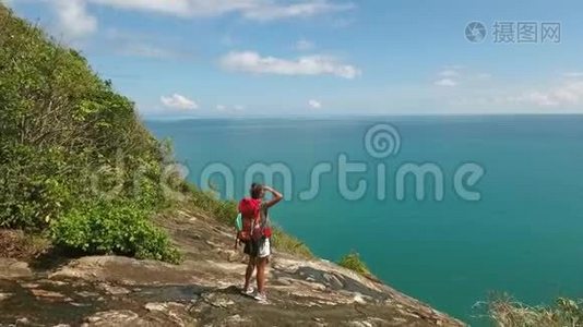 空中：年轻的远足女孩站在山岩上欣赏海景。 泰国Koh Phangan。视频