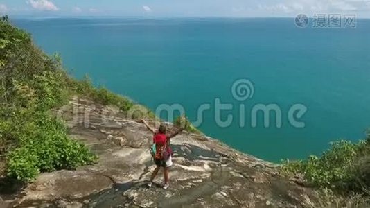 徒步旅行女孩站在山岩与伸展的手臂。 泰国Koh Phangan。 空中高清慢速运动。视频