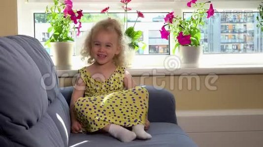 可爱的情绪蹒跚学步的女孩，穿着黄色连衣裙坐在沙发上，表现出情感视频