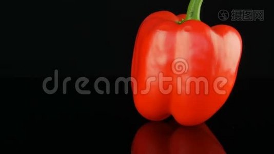 美丽的大熟红色甜椒辣椒在镜面和黑色背景上旋转。视频