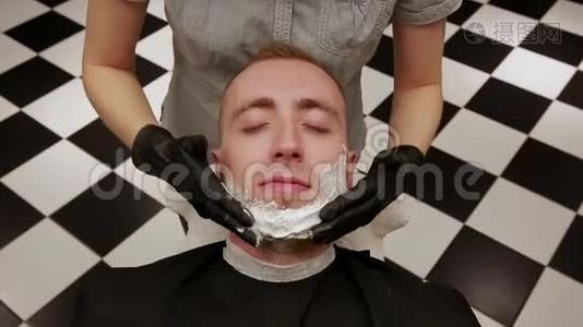 一个男人的特写脸铺着剃须泡沫。 理发店，理发店。视频