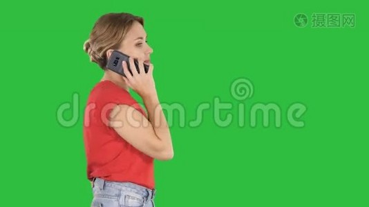 金发女人在绿色屏幕上走来走去，在电话里说话，Chroma键。视频
