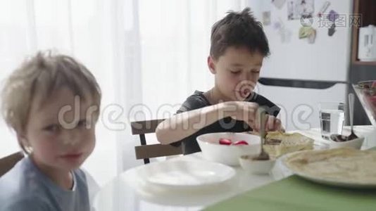 孩子们把草莓卷成薄饼. 孩子们吃煎饼。视频