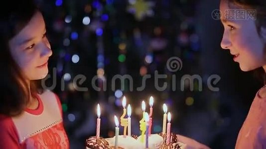 两个小女孩正在看生日蛋糕上的蜡烛。视频