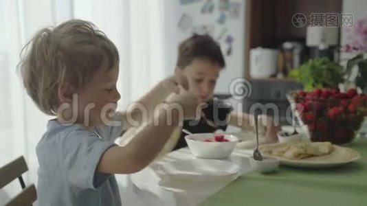 孩子们把草莓卷成薄饼. 孩子们吃煎饼。视频