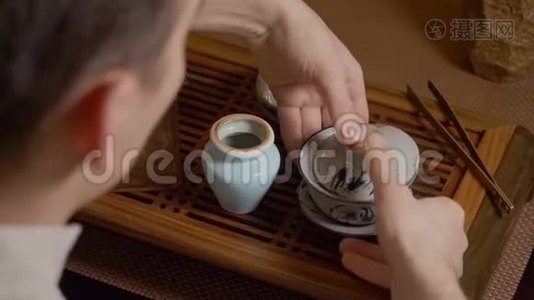 师傅把盖湾的绿茶倒在碗里。 中国茶道仪式视频