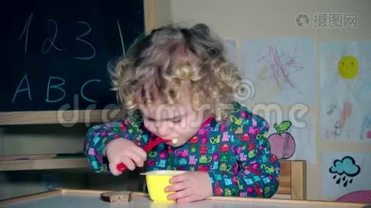 女孩用勺子吃最喜欢的酸奶。 幼儿用舌头舔塑料勺子视频