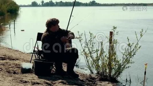在河边钓鱼的时候，年轻的渔夫在旋转鱼卷视频