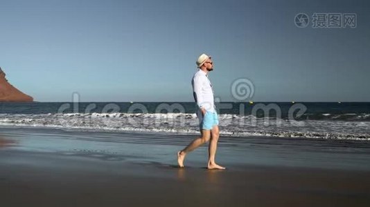 日落时沿着海边散步的快乐男人。 无忧无虑的现代生活理念.. 西班牙加那利群岛特内里费视频