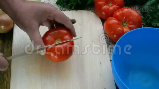 自制素食健康食品.. 人类的手切出红色多汁的西红柿来做蔬菜沙拉。视频