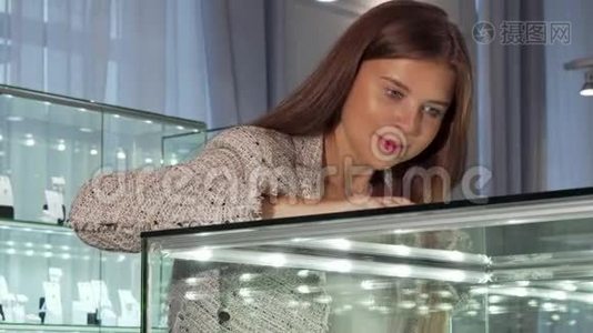 年轻女子在珠宝店的橱窗里看视频