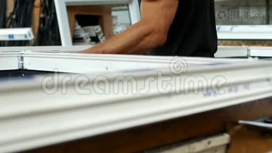 制造和制造PVC窗户，一名男性工人在PVC框架中安装橡胶密封，组装PVC。视频