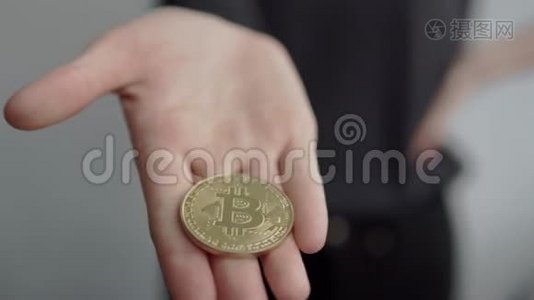 女人一手拿着加密货币黄金比特币硬币，在镜头中展示。 电子虚拟货币。 银行业务视频