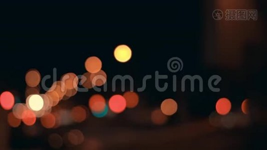 夜晚城市背景的灯光。 城市交通中移动汽车的离焦前灯。 抽象的，明亮的，闪光的，彩色的视频