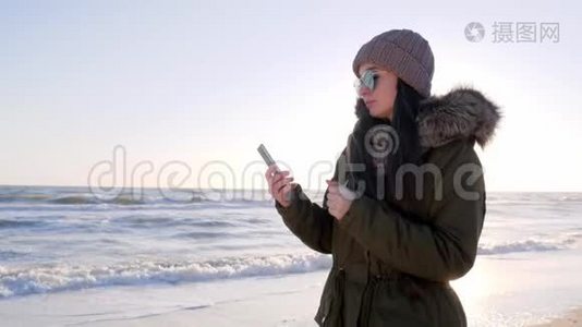 网瘾，戴眼镜的女人在海边带智能手机视频