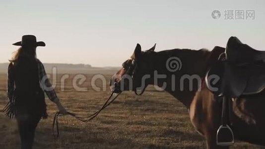 日出时，年轻的女孩骑着她那黑色美丽的马走在缰绳旁。视频