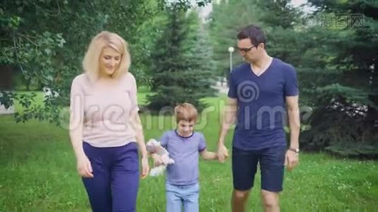 成年父母和小男孩一起在绿色公园散步视频