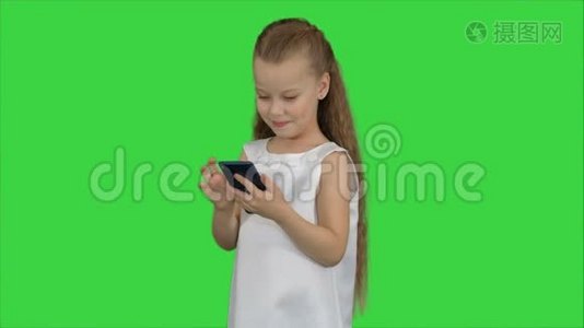 小女孩在绿色屏幕上使用智能手机，色度键视频
