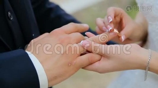 新娘和新郎在绿色自然背景下交换结婚戒指视频