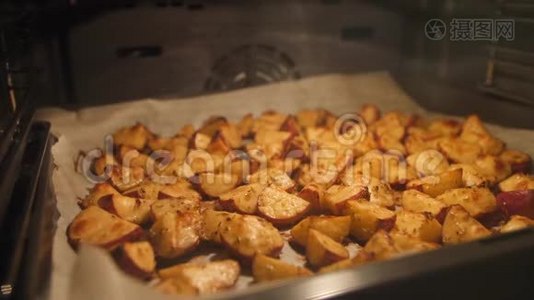 烤土豆与迷迭香，大蒜，胡椒和百里香在烤箱。 健康素食饮食或烹饪食谱概念4K页。视频