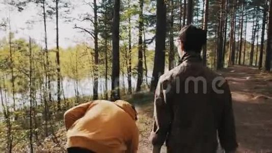 在森林里和朋友散步的时候，男人拿起石头扔进湖里视频